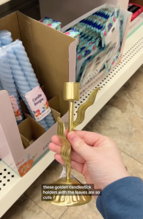 shopper holding gold dollar tree candle holder
